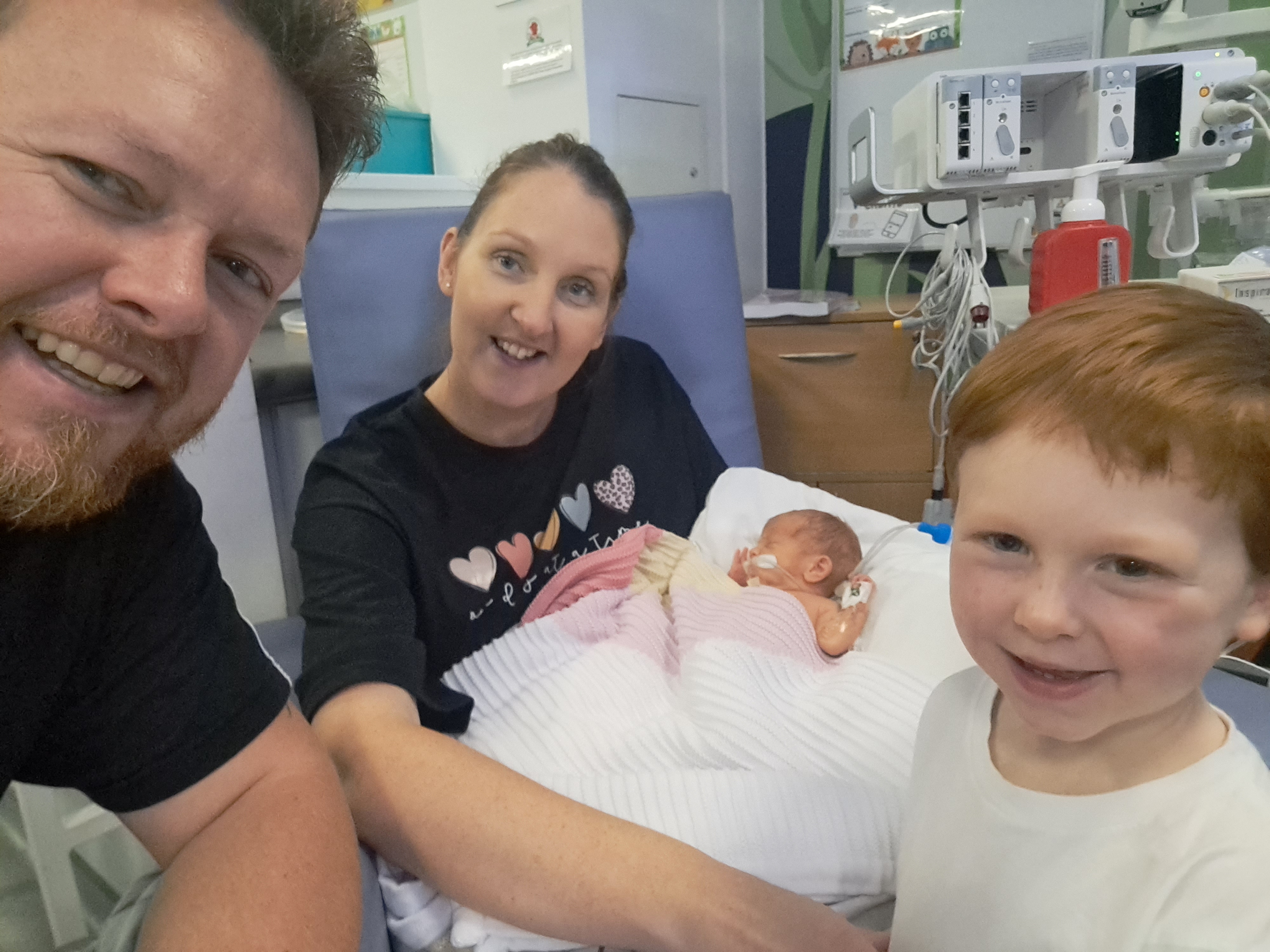The family together with Imogen in the NICU
